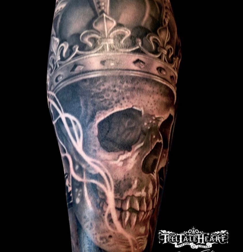 black and grey tattoo of a realistic skull wearing a crown