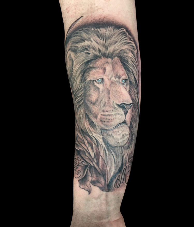 soft black and grey portrait of male lion head on forearm with tulips and names in script tattooed on forearm