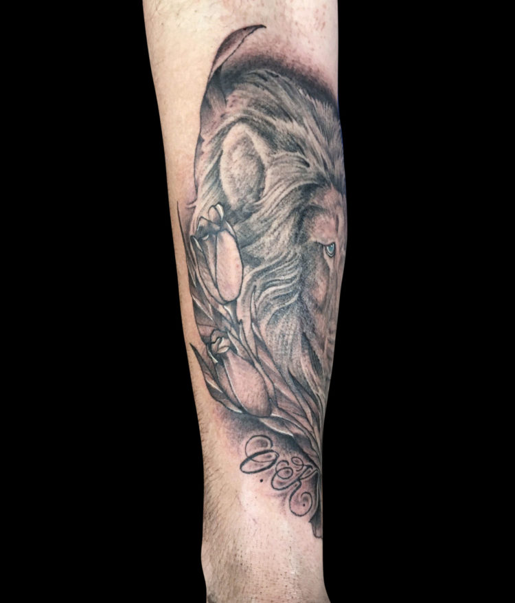 detail of lilies tattoo next to lion portrait black and grey