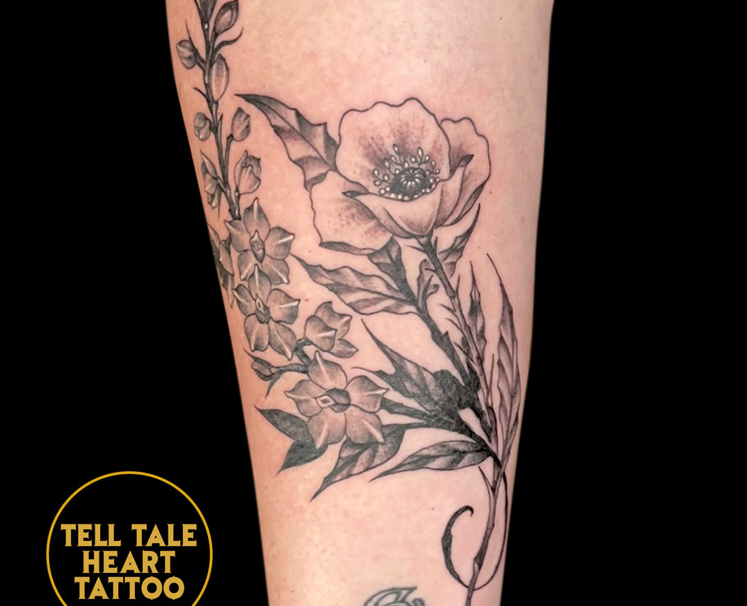 delicate tattoo of black and grey flowers with stem one large flower, many smaller ones