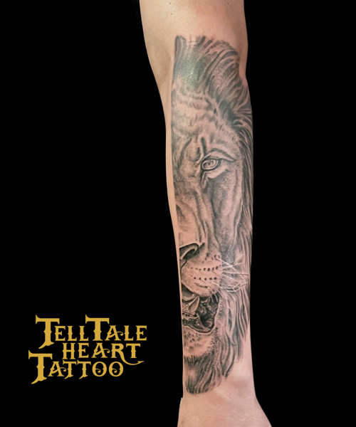 Black and grey tattoo of half of lion face on forearm