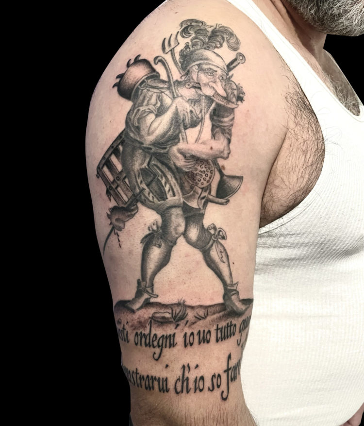 black and grey tattoo of a medieval illustration of a cook with latin text underneath on outside of arm