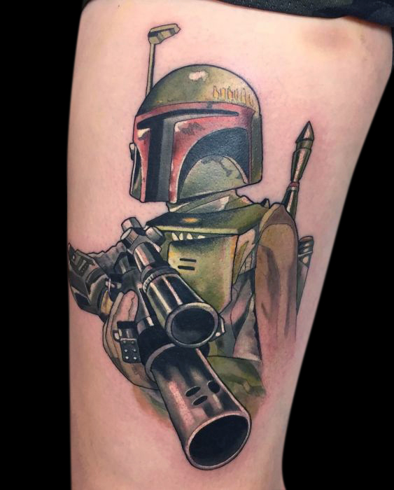Colour tattoo of Boba Fett from Star Wars pointing his blaster toward us from the waist up tattooed on inside of thigh