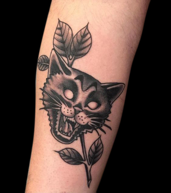 black and grey cat head tattoo meowing with a branch and leaves in background