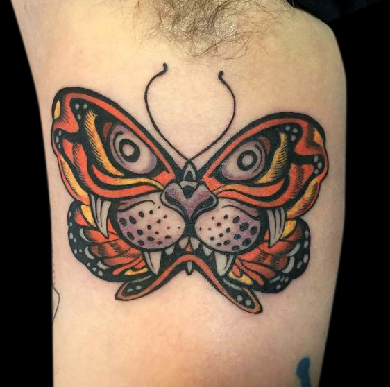 colour tattoo of Japanese tiger face inside the shape of a butterfly with fangs bared done in orange, purple, yellow and black outline