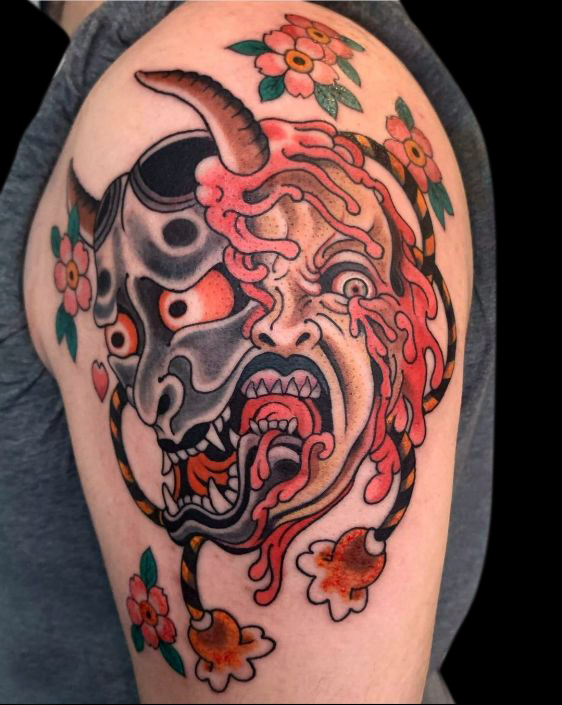 Japanese hanya monster mask with grotesque face underneath and cherry blossoms on shoulder