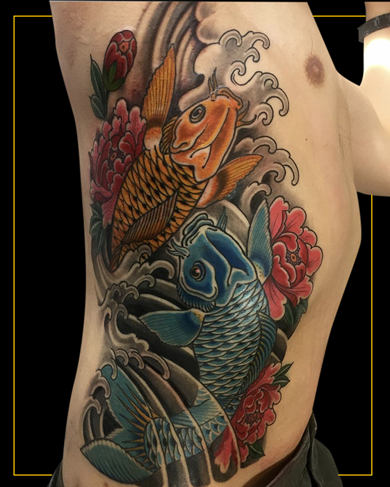 Japanese tattoo of two colour koi fish, orange and blue, with red flowers swimming upwards on a person's side with Japanese finger waves and water