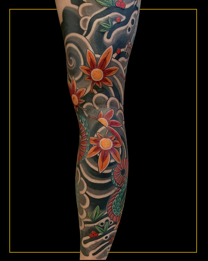 Japanese leg sleeve tattoo with Japanese maple leaves, rocks, wind bars and clouds