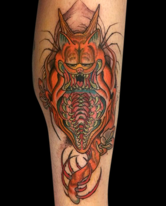 tattoo of Garfield cartoon cat as a monster with a vertical opening on its body filled with rows of teeth and a spiked tail