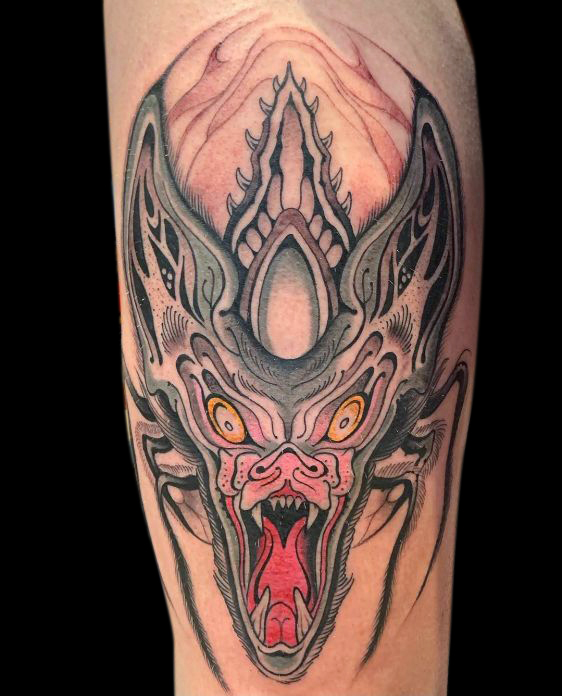 tattoo of bat monster screaming with open mouth, yellow eyes and huge ears with spider legs