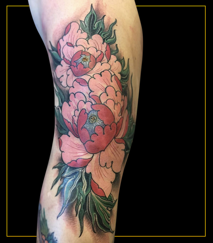 Japanese pink peonies on front of knee and green leaves extending onto thigh and shin