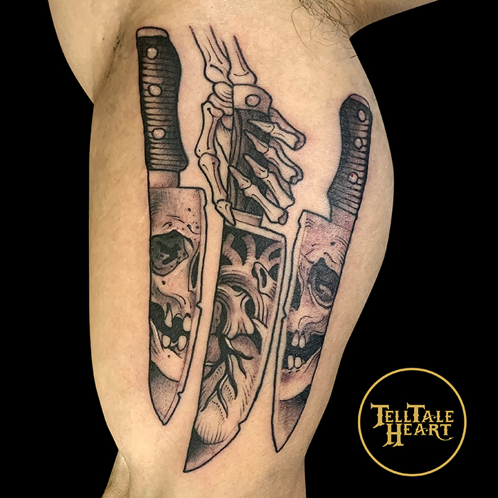 black and grey tattoo of three chef's knives side by side the middle being held by a skeleton hand with a skull in the reflection of the knives and an anatomical heart in the middle knife relfection.