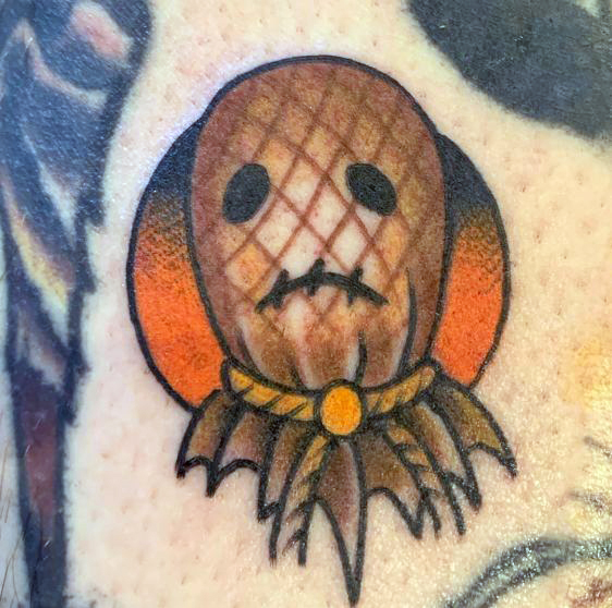 Cute scarecrow head tattoo with an orange sun behind it