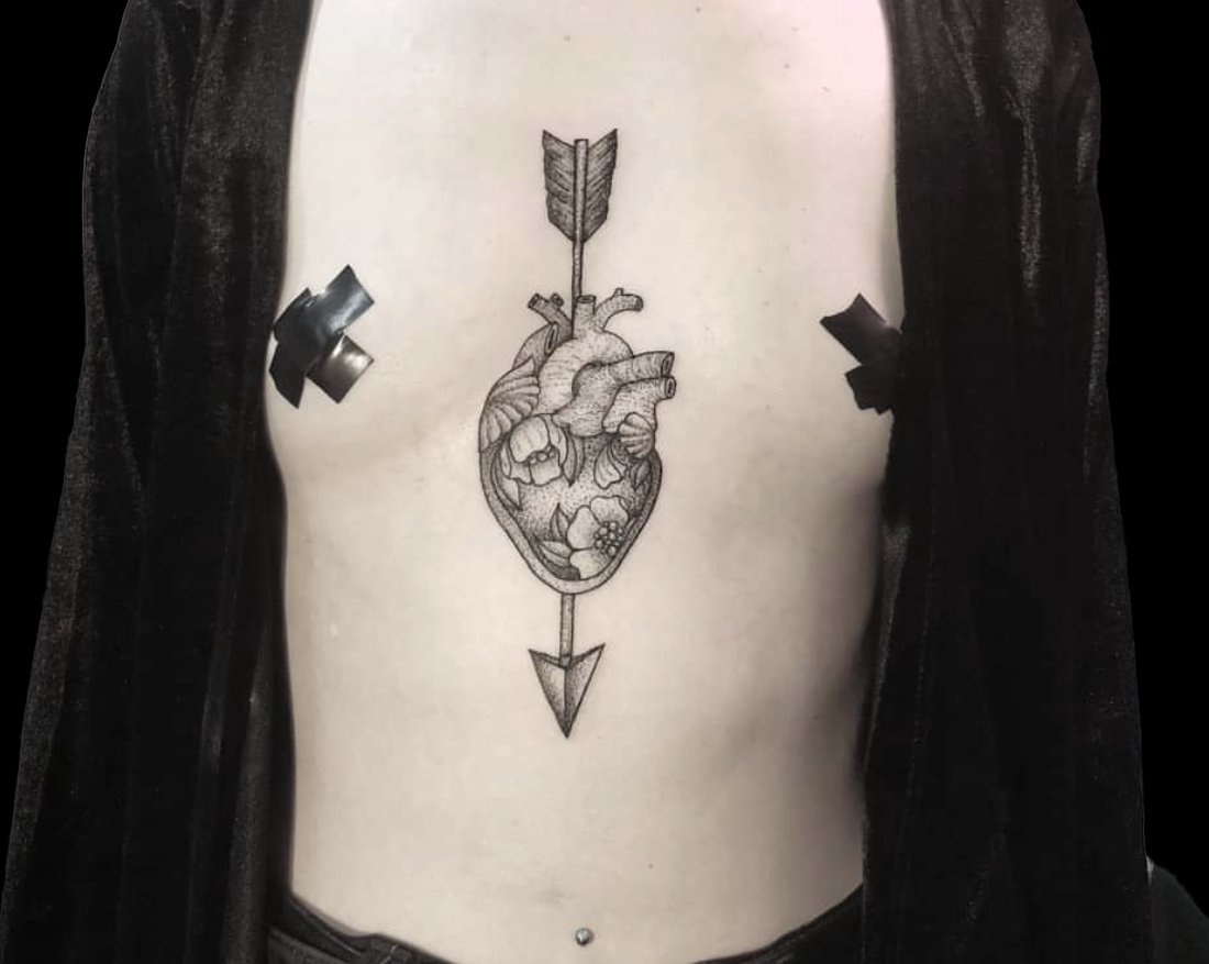 dotwork tattoo of anatomical heart with floral petals inside it and arrow piercing through the top of it and head poking out the bottom tattooed on sternum