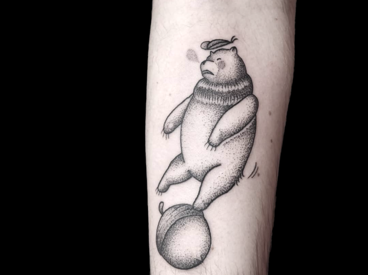 dotwork tattoo of a bear and acorn shaded with dots on forearm