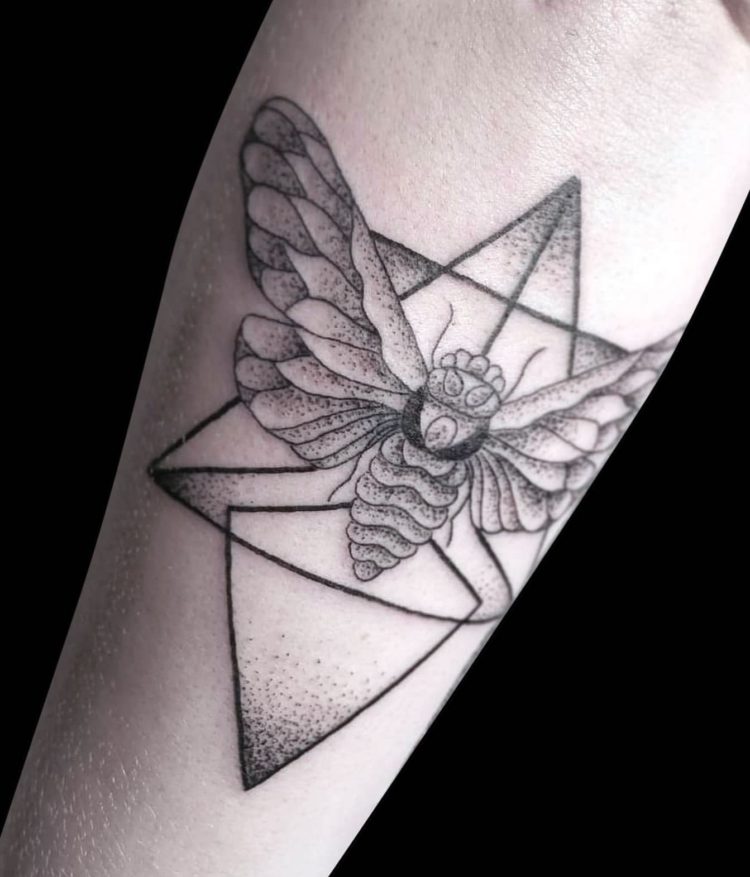 blackwork geometric design of moth and triangles in background shaded with dotwork tattooed on back of forearm