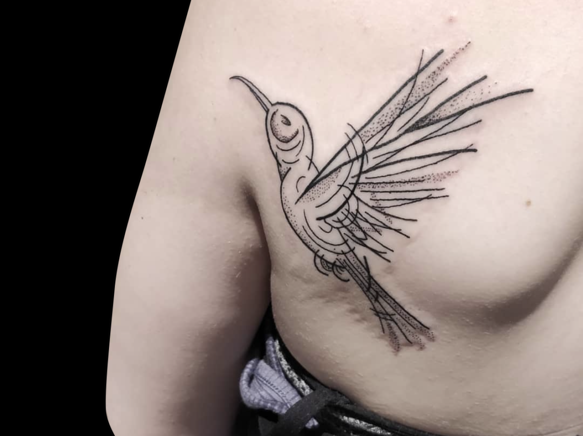 illustrative tattoo of flying bird with simple lines and dotwork shading tattoed on back of shoulder