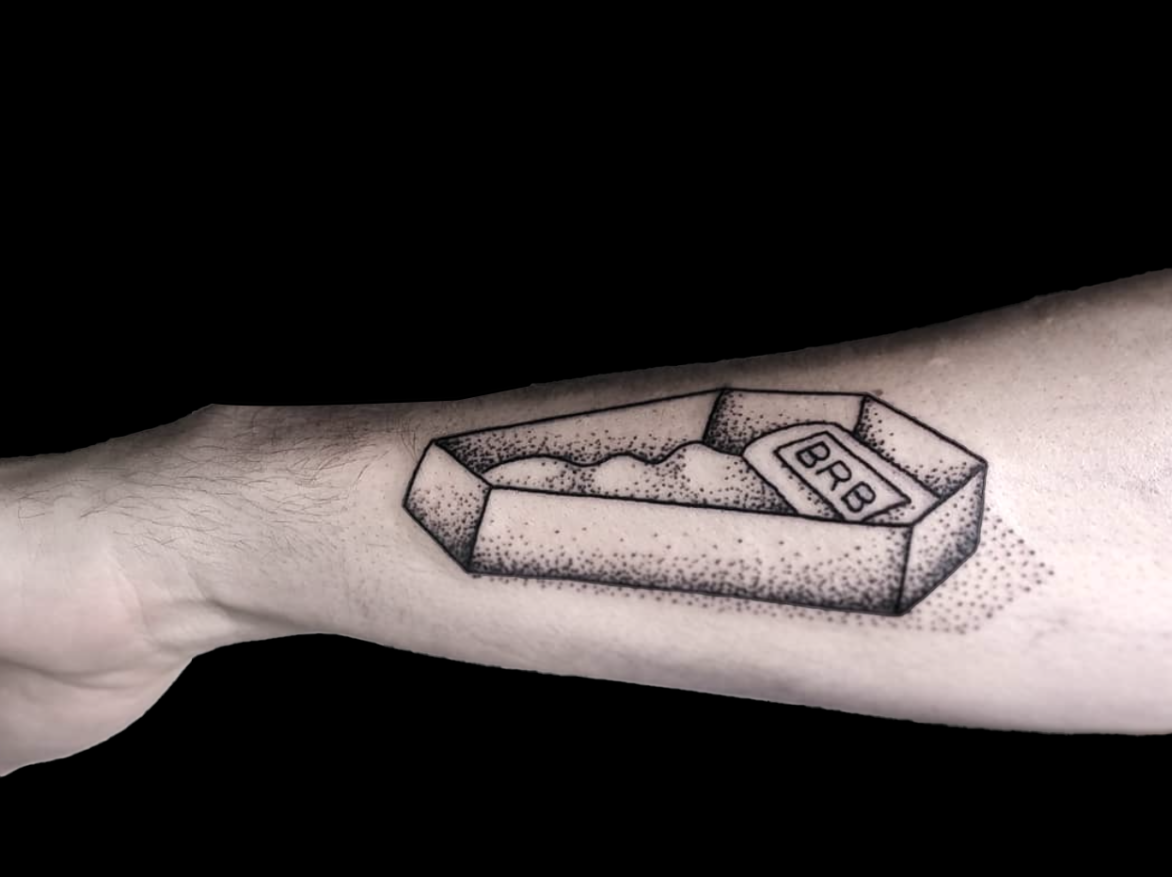 dotwork tattoo of open coffin with sign that says BRB shaded with simple dots tattooed on forearm