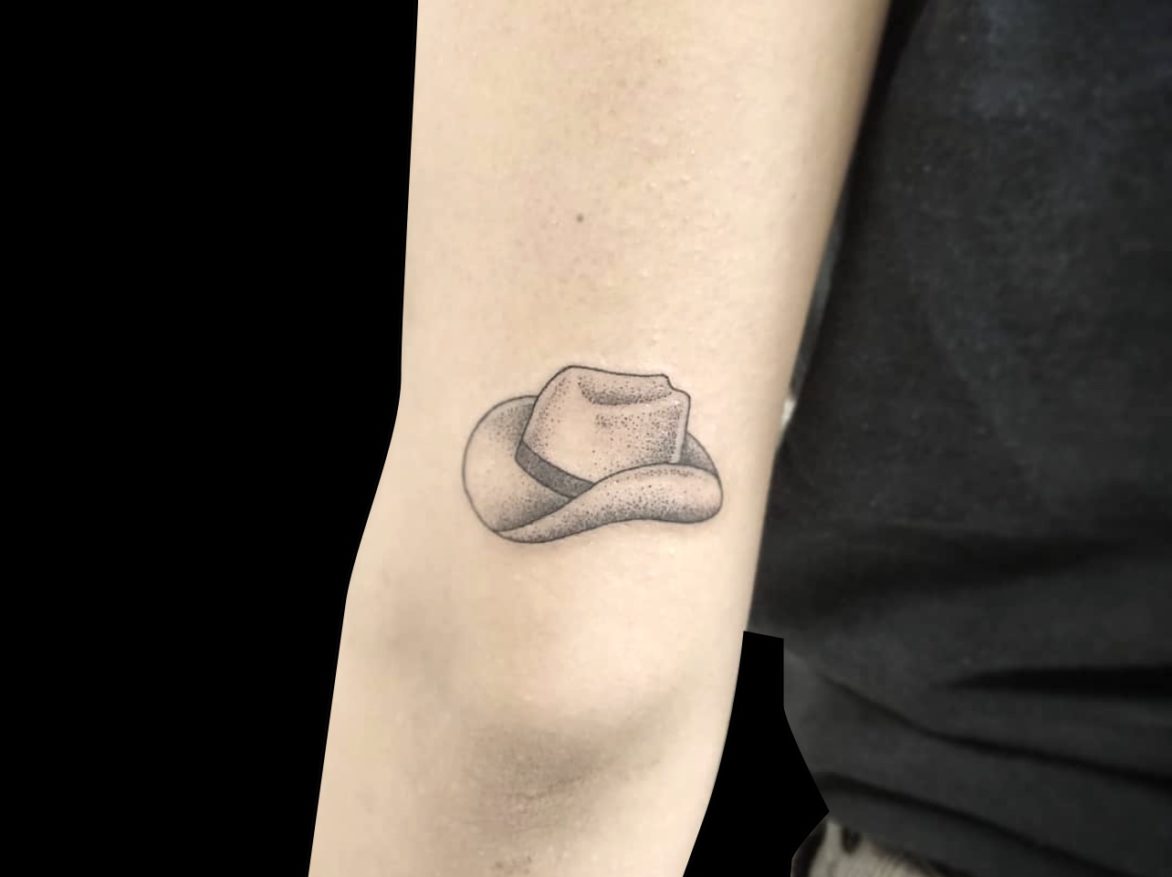 micro tattoo small simple cowboy hat shaded with black dotwork just above back of elbow