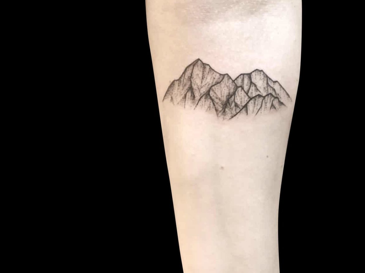 small fineline tattoo of a mountain range with two peaks tattooed on forearm shaded with dotwork
