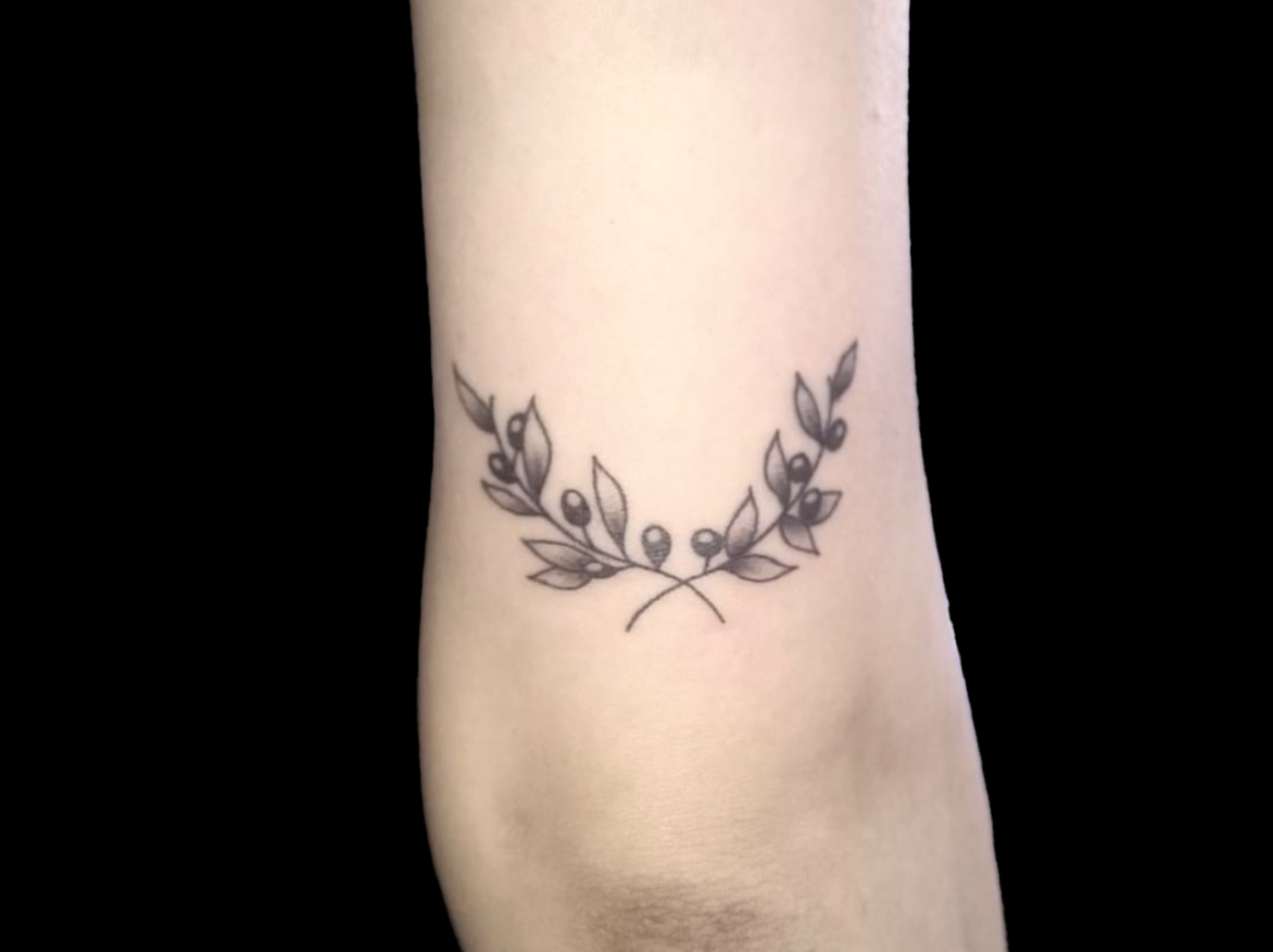 simple pair of black olive branches tattoo crossed above back of elbow