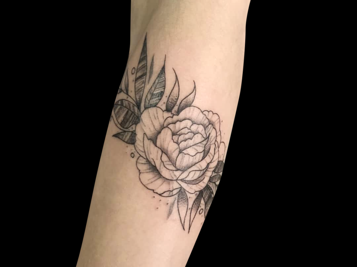 fineline tattoo of a single peony with leaves tattooed on forearm