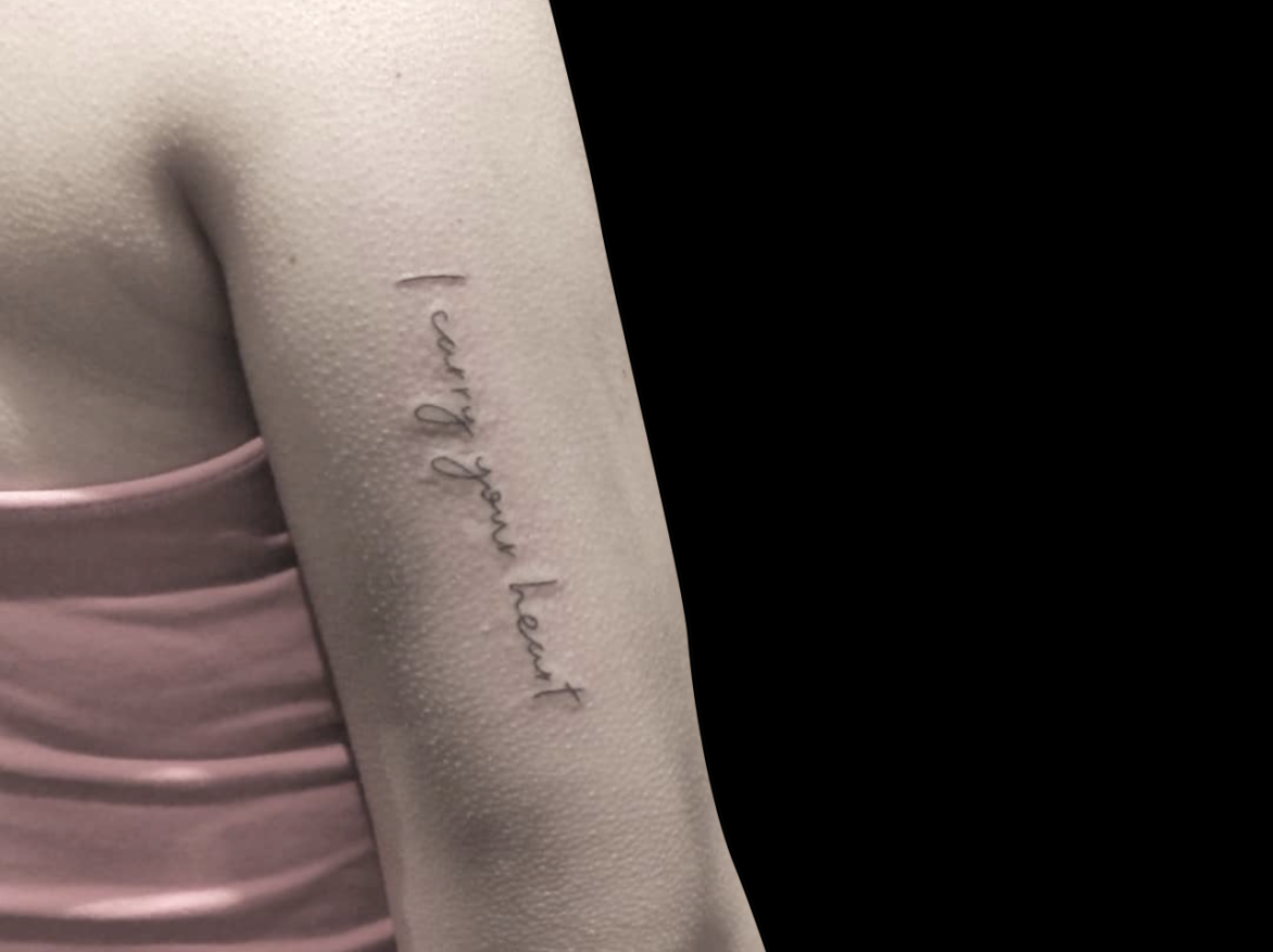 fineline tattoo of script that reads I CARRY YOUR HEART on back of tricep