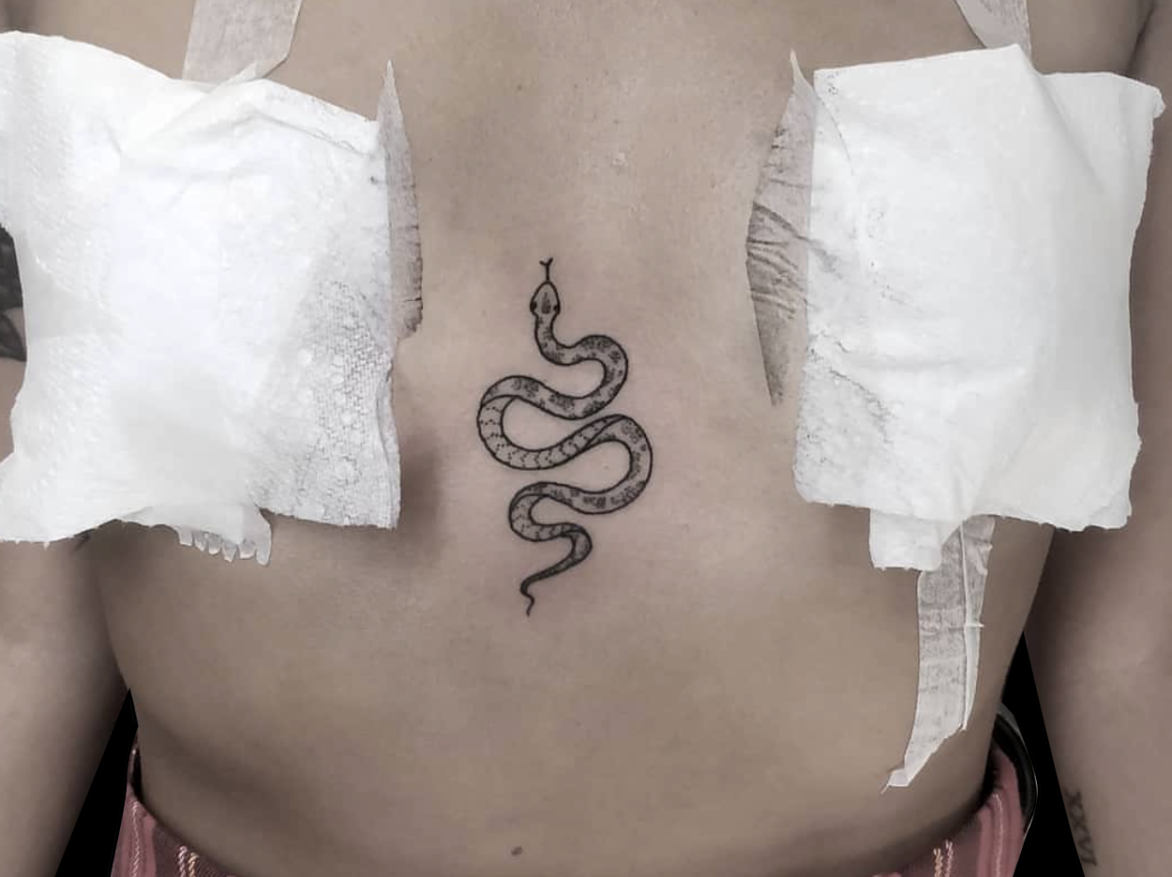 fineline tattoo of a simple snake head pointing upward on a sternum