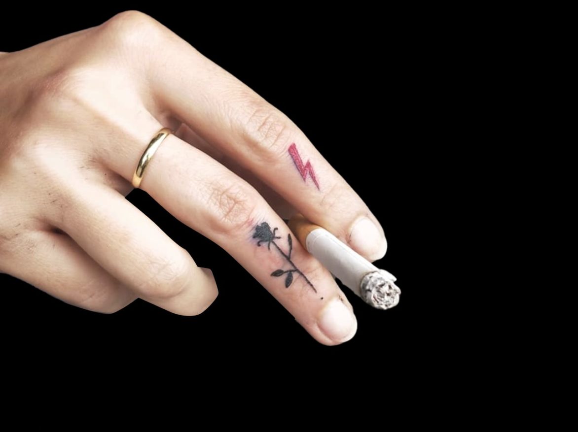 micro tattoos on fingers of a red lightening bold on index finger and black solid rose on middle finger