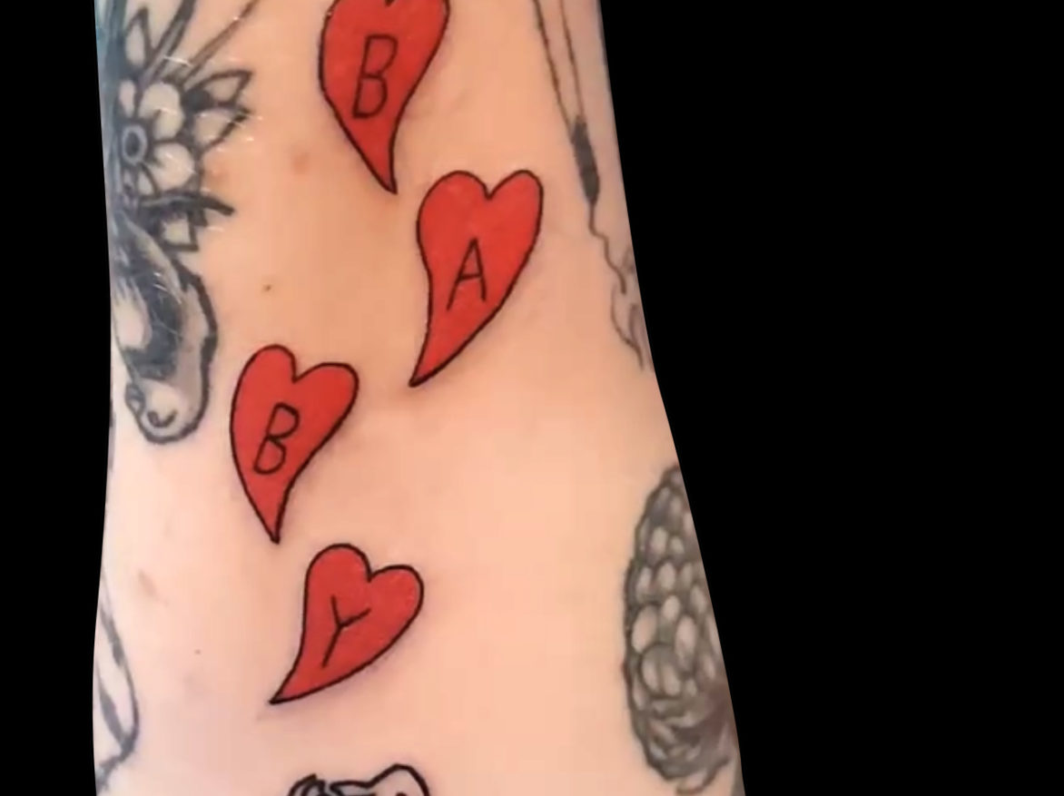 tattoo of four red hearts stacked with one letter in each spelling out the word BABY