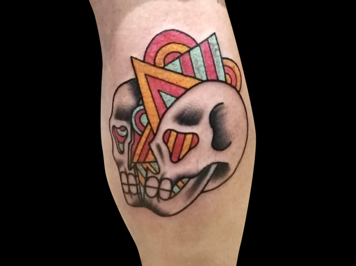 abstract tattoo of a traditional skull split in two with rainbow geometric shapes triangle, circles and sqaures coming out of the center tattooed on back of calf