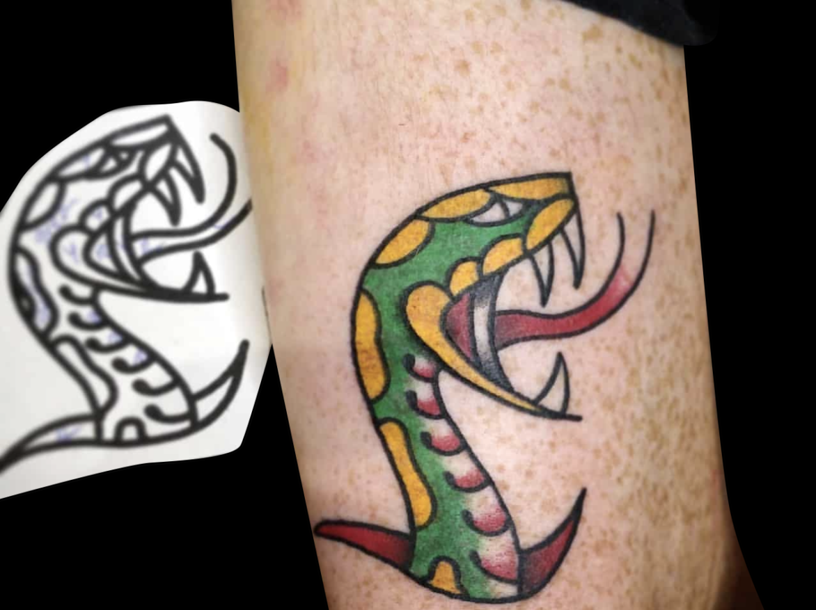 traditional colour tattoo of a green and yellow snake head profile with mouth open and tongue out coming out of slit in skin