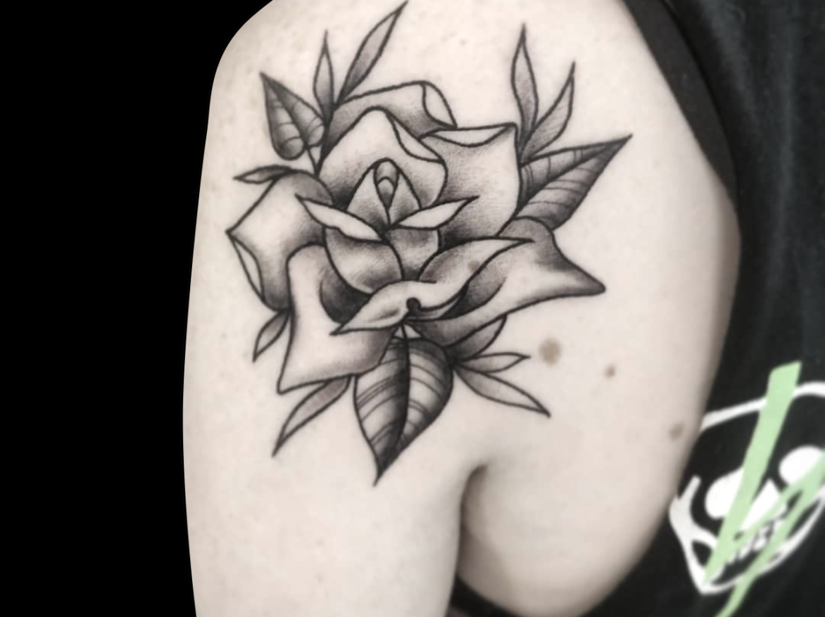 black and grey tattoo of a rose shaded with soft grey on the back of shoulder