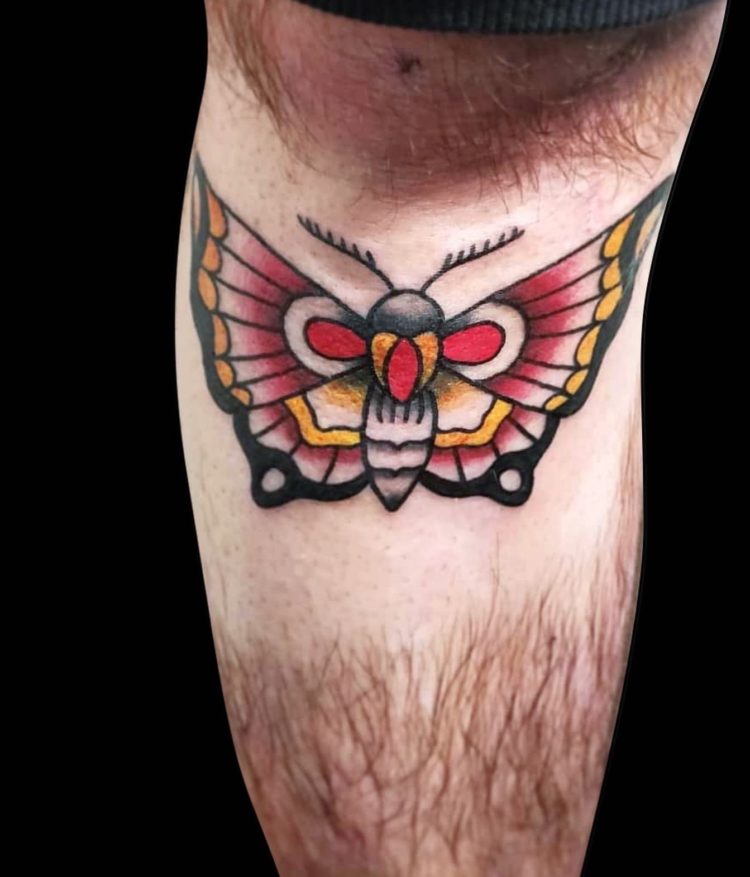 traditional colour tattoo of butterfly with red, yellow and black body tattooed on shin just under the knee