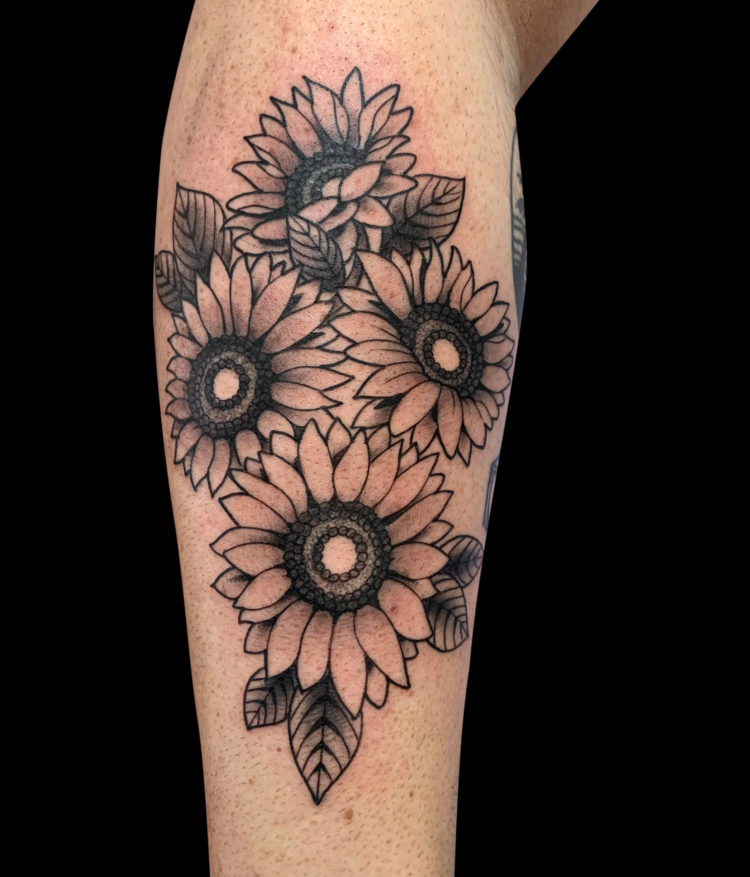 black and grey tattoo of four sunflowers and simple leaves on forearm