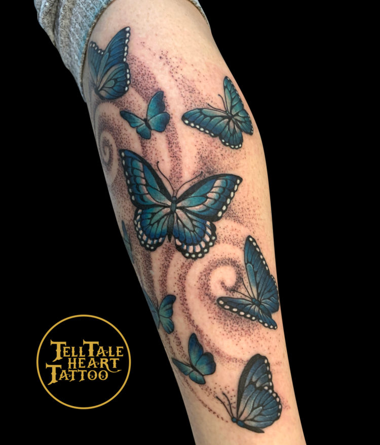 colour tattoo of eight blue butterflies with swirling dotwork background on side and back of calf