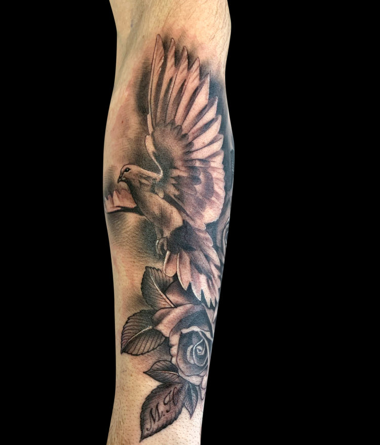 black and grey realism tattoo of a profile of a dove with it's wings raised and a rose below it