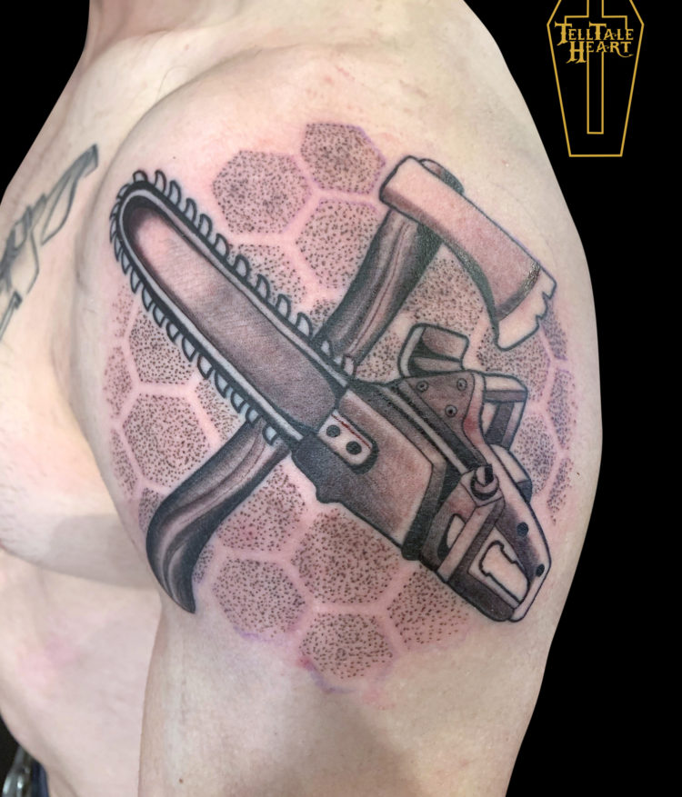 Evil Dead themed tattoo of a chainsaw and and axe crossed with background made up of geometric dotwork pentagons on deltoid