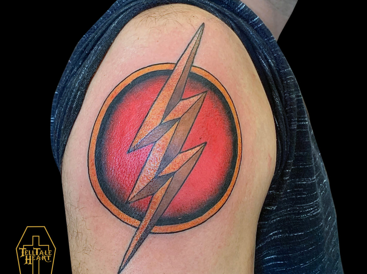large colour flash tattoo logo featuring red circle with yellow outline and large yellow lightening bolt in the middle tattooed on shoulder