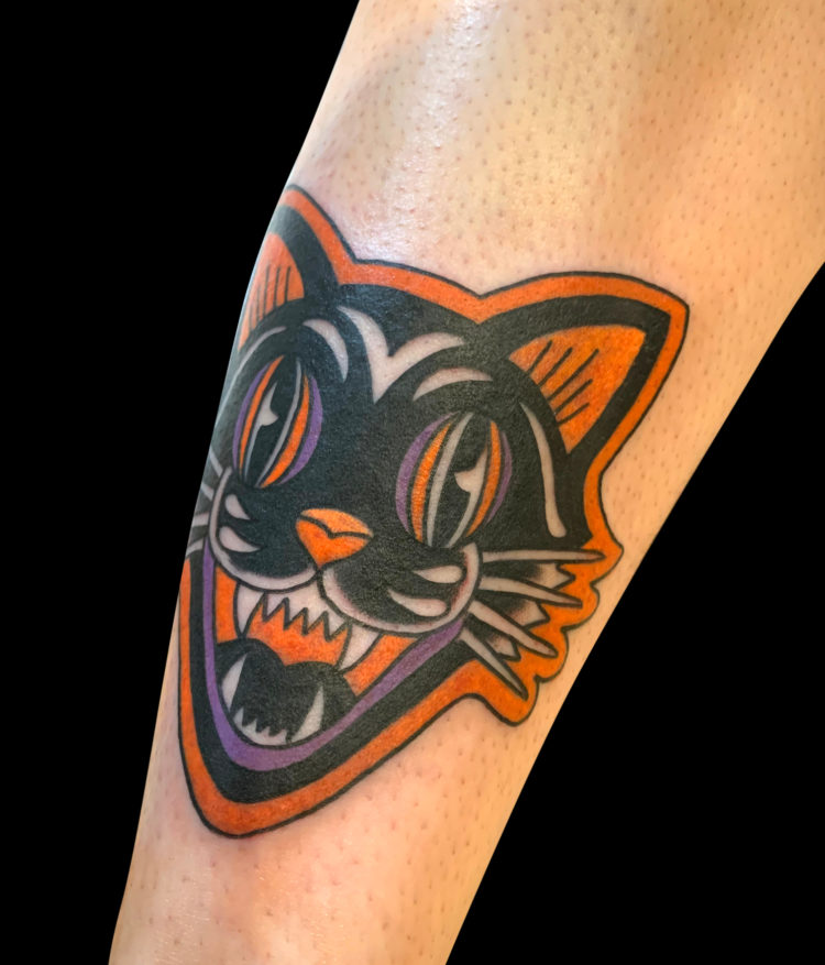 Halloween themed stylized screaming cat face tattoo in black, orange and purple