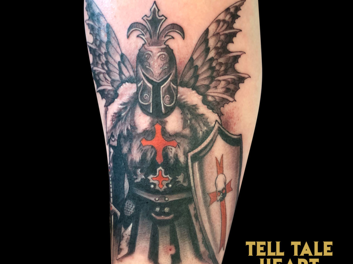 black and grey tattoo of medieval knight with wings holding a sword and sheild with red iron crosses