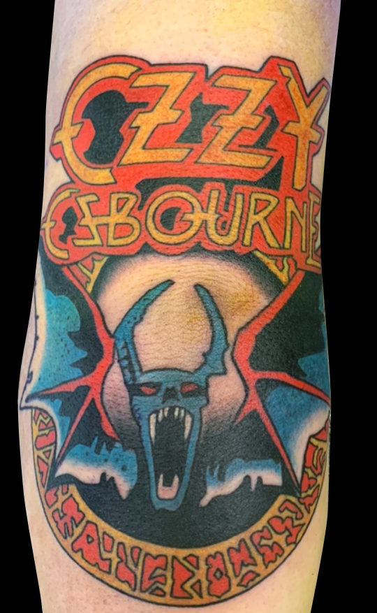 colour tattoo of Ozzy Ozbourne logo with bat in blue, red and yellow