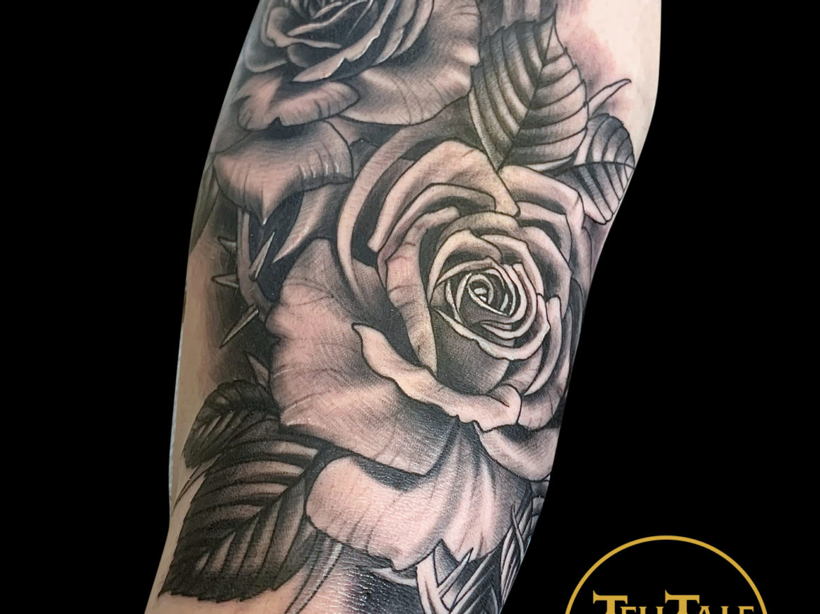 black and grey realism tattoo of two large roses with leaves and soft grey background