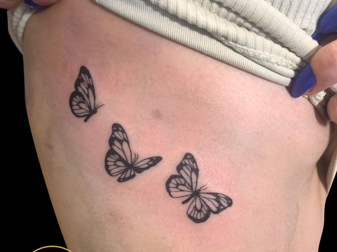 blackwork fineline tattoo of three simple butterflies on ribs