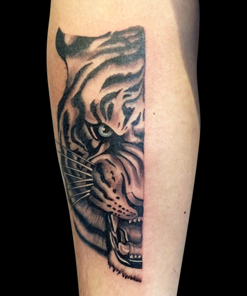 black and grey tattoo of half of a tiger's face with blue eyes