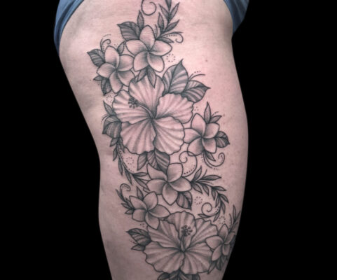 black and grey flowers tattooed on the outside upper thigh.