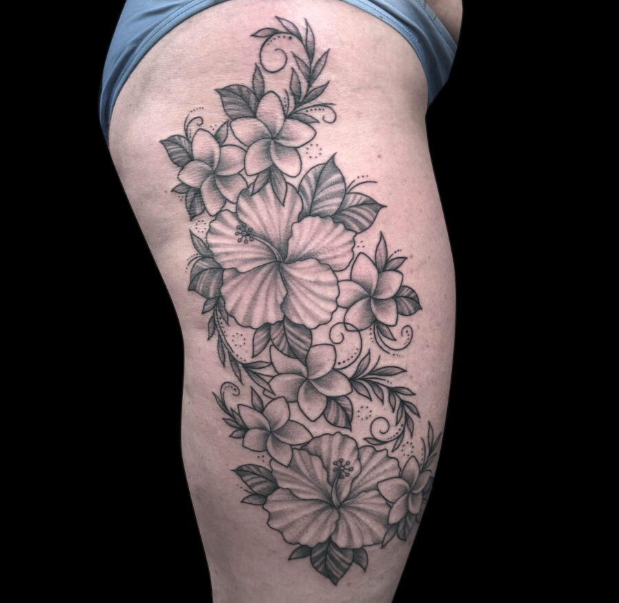 black and grey flowers tattooed on the outside upper thigh.